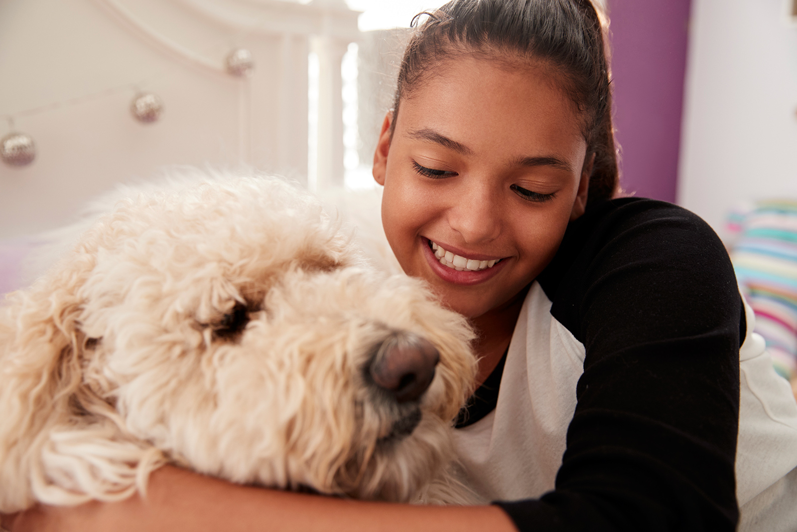 young-teen-girl-embracing-pet-dog-on-her-bed-PGQHKBW.jpg